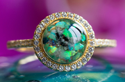 Photo depicts our Bedazzled Circle Opal Cremation Ring, in the colors green and black, sitting on a glass surface. Sterling Silver Ring, Sterling Silver Ring for Ash, Ring for Cremation Ash, Sterling Silver Remembrance Jewelry, Sterling Silver and Cubic Zirconia Ring